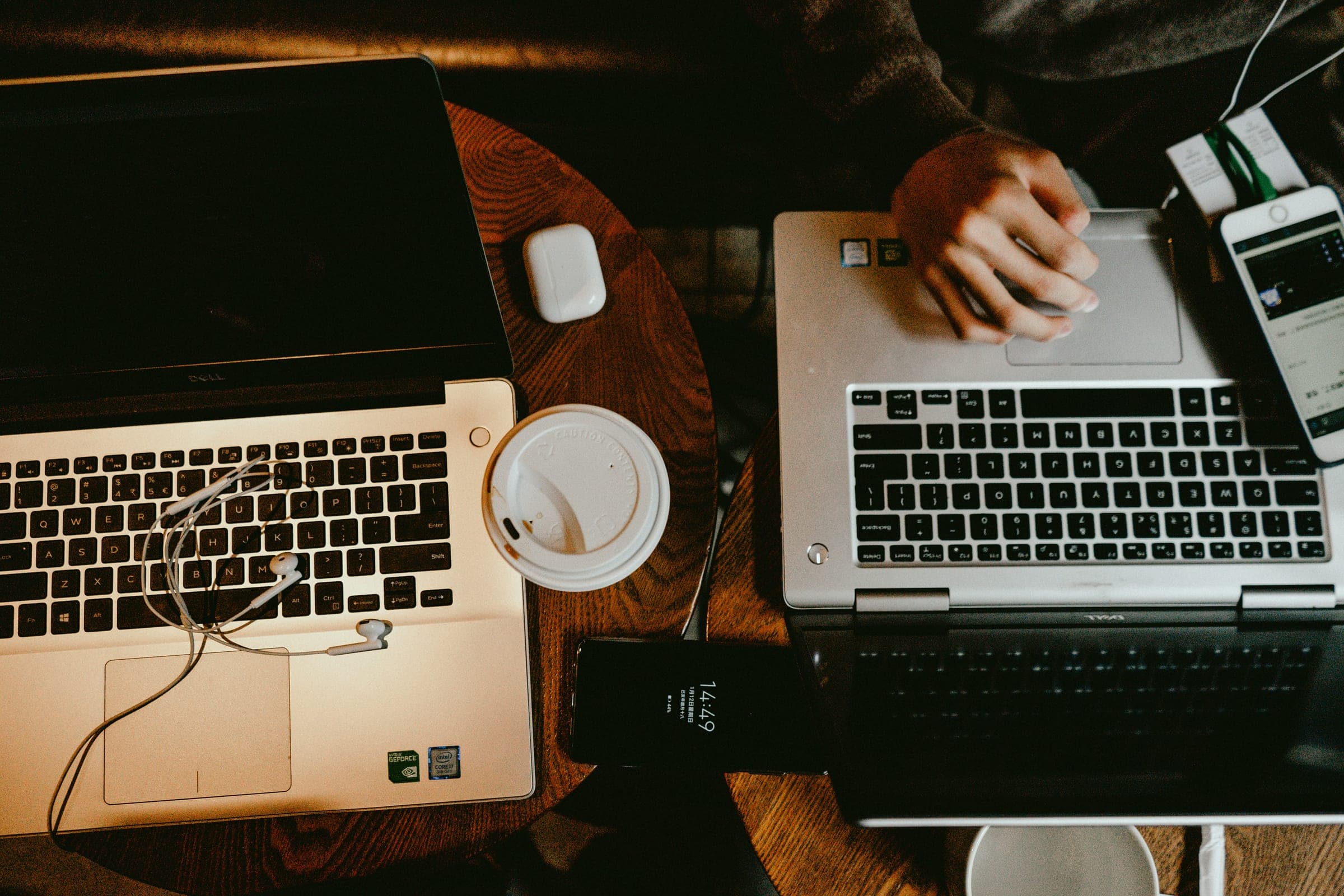A person working on the laptop while another works with papers.