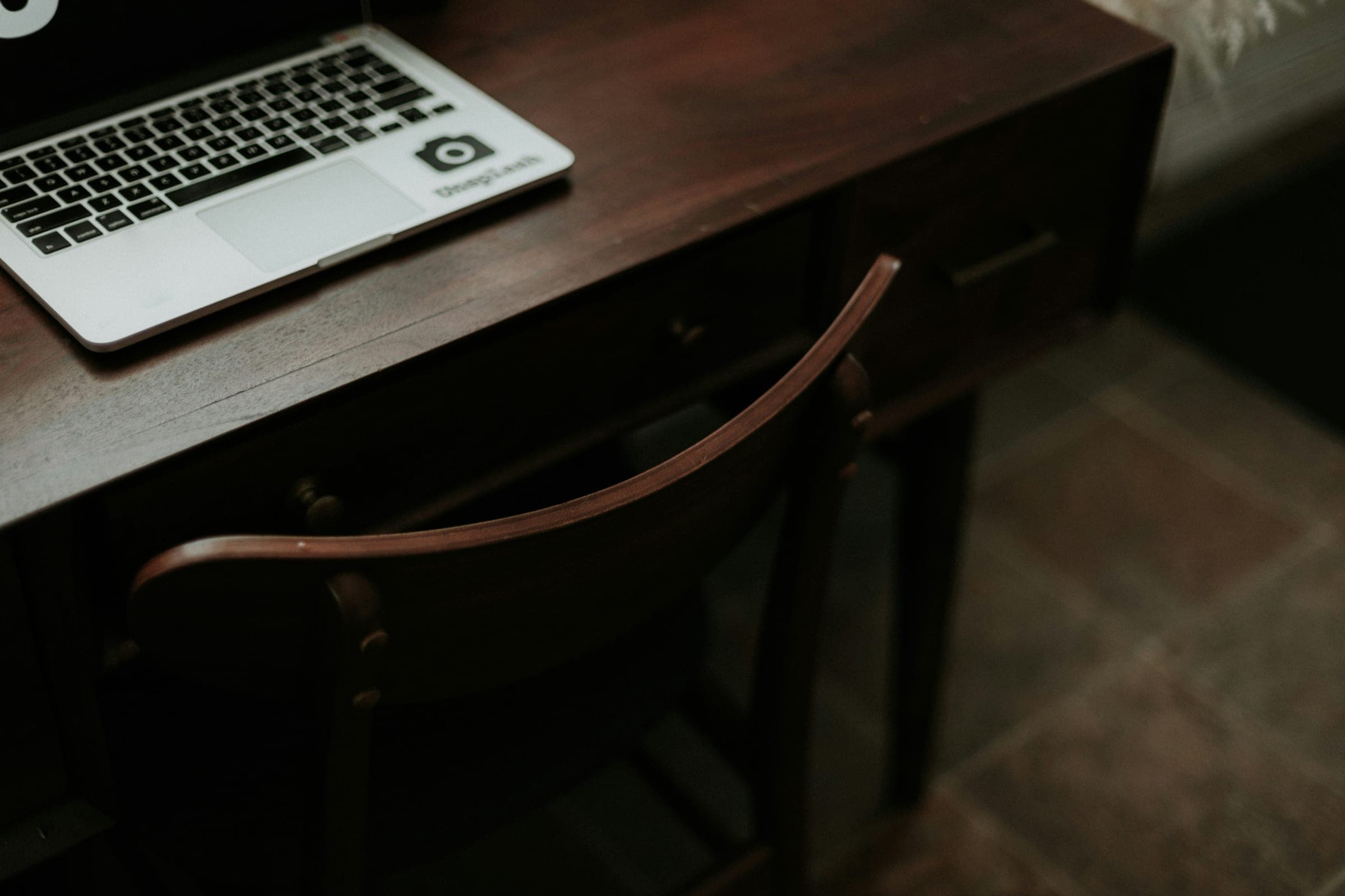 A small desk with a laptop and an enclosure.