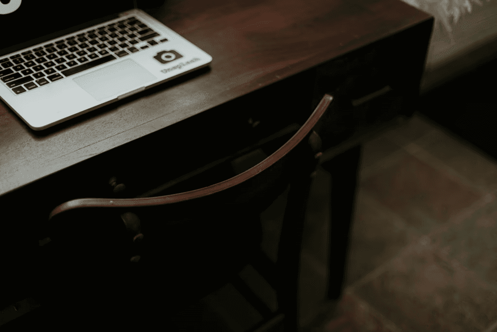 A small desk with a laptop and an enclosure.