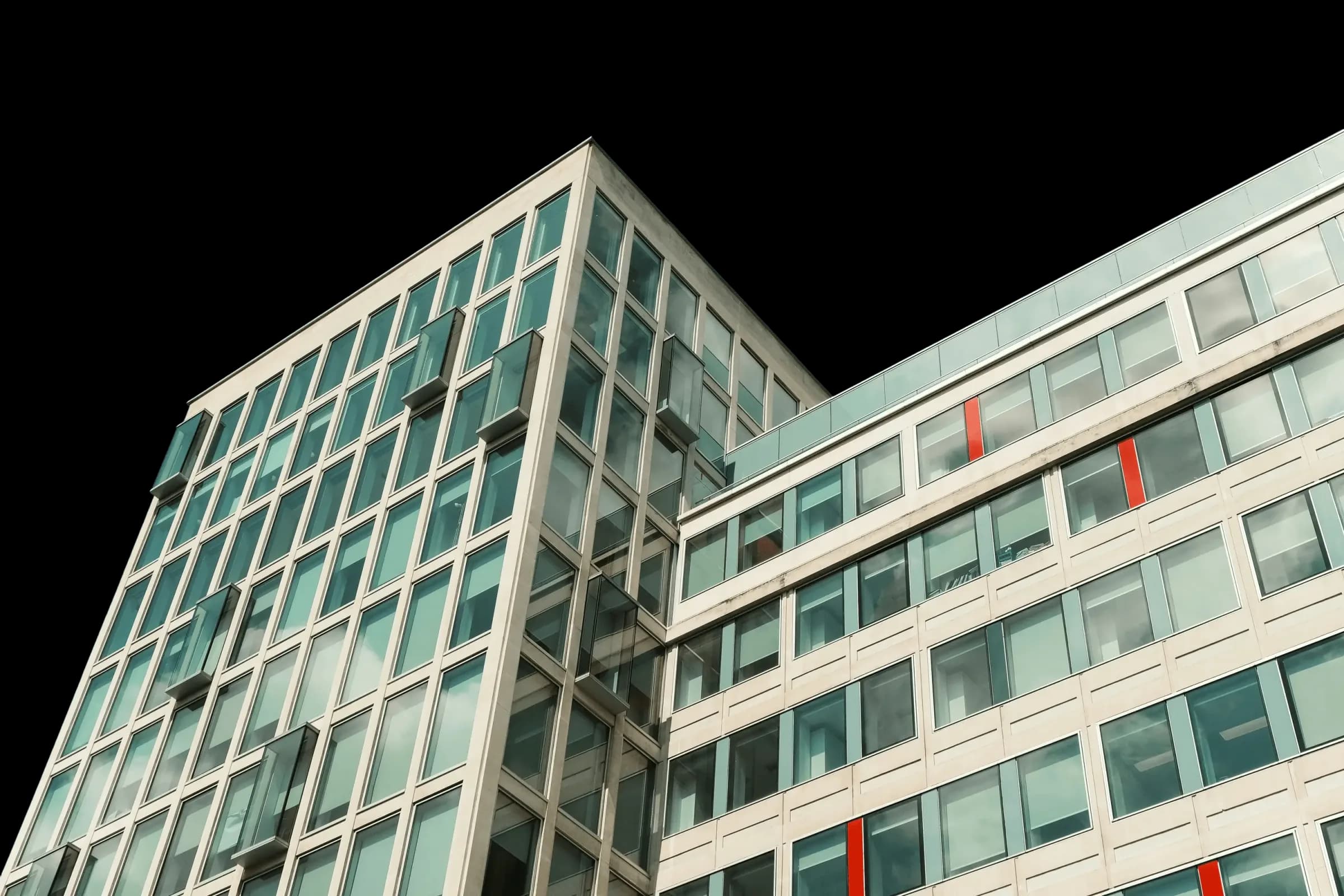 Blick von oben auf ein modernes Bürogebäude aus Glas vor klarem blauem Himmel