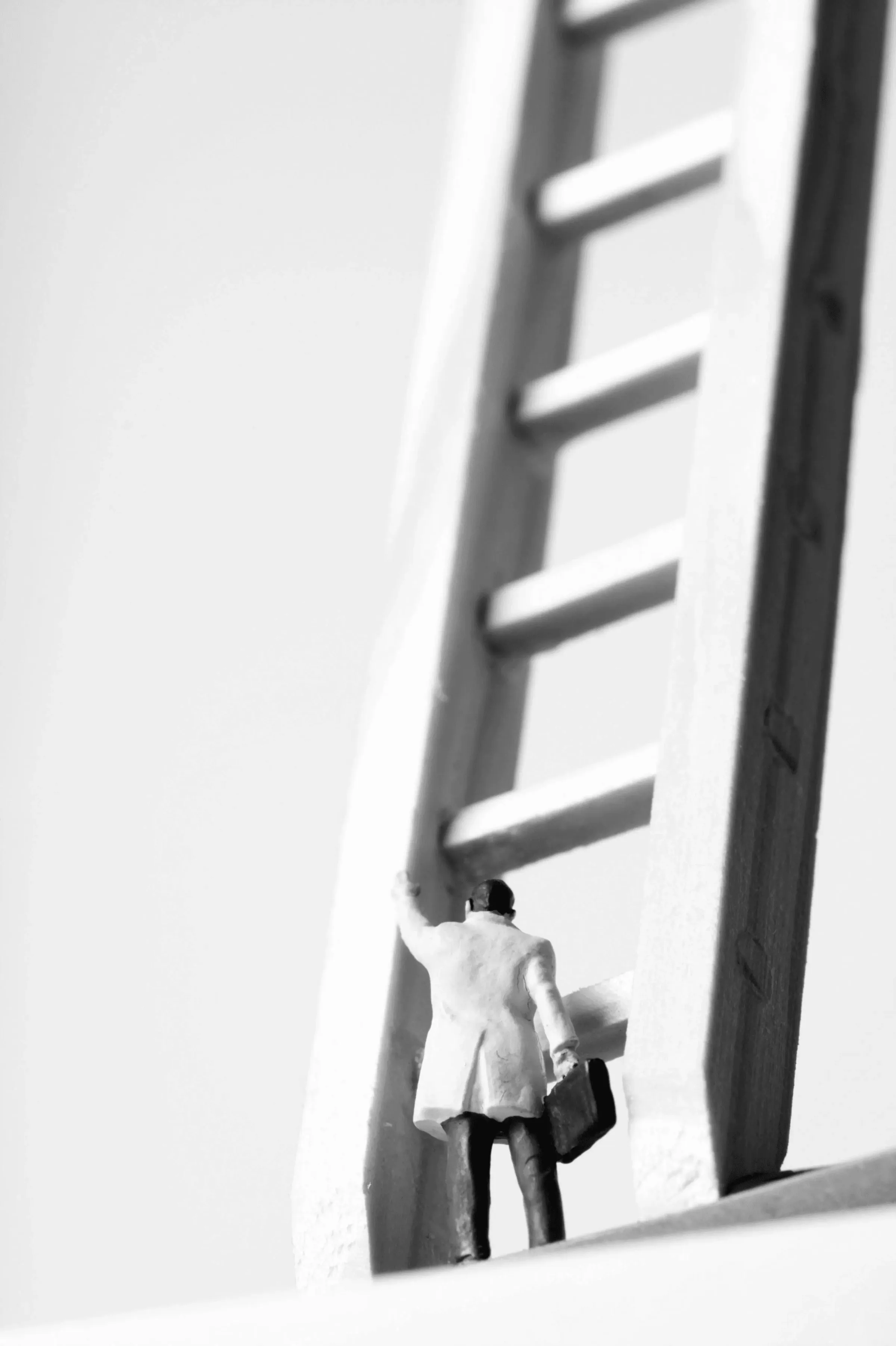 Ein surreales Bild einer kleinen Person im Anzug, die eine riesige Leiter zu einer Tür hinaufsteigt