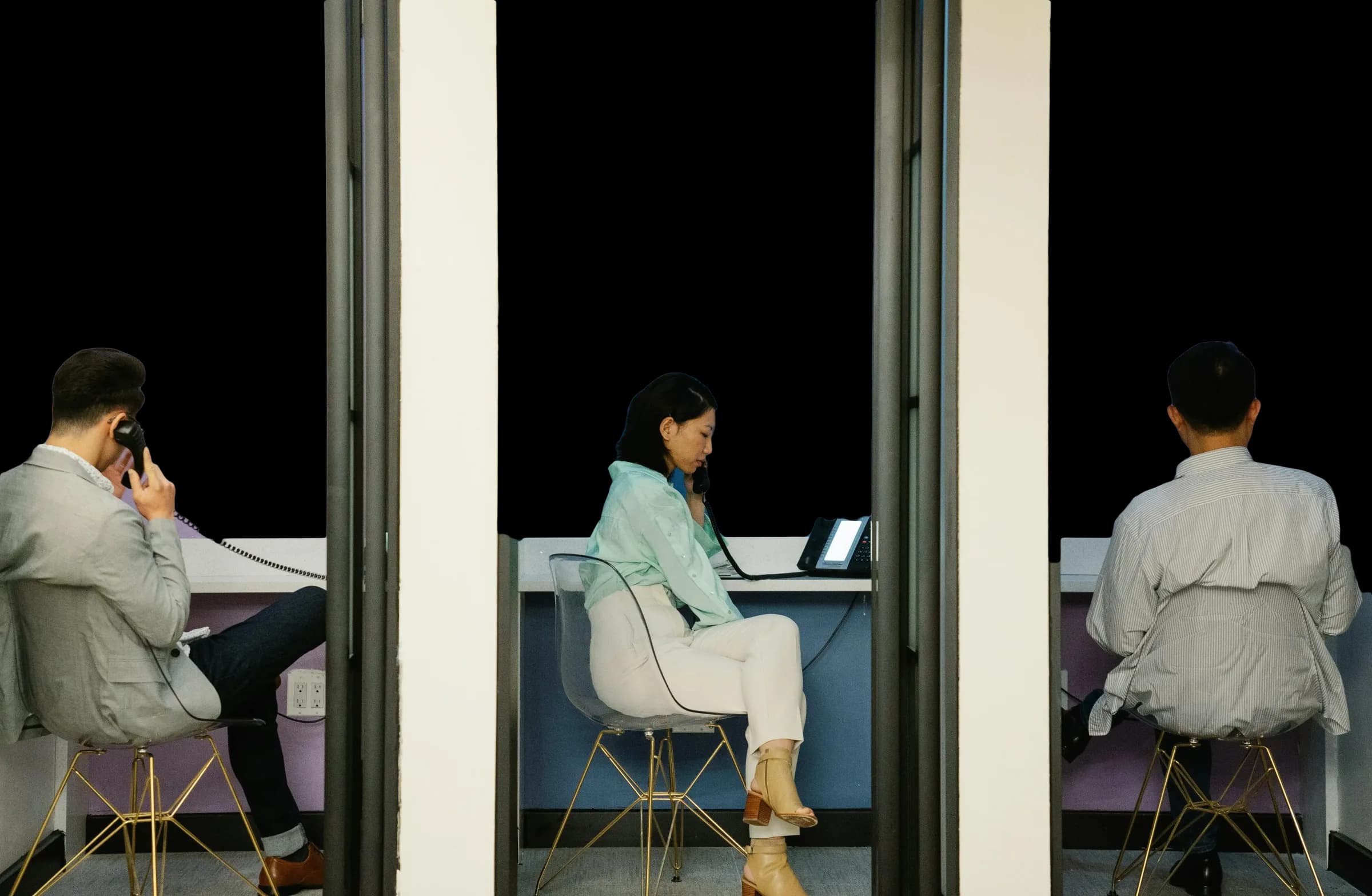 Zwei Personen telefonieren in getrennten Bürokabinen