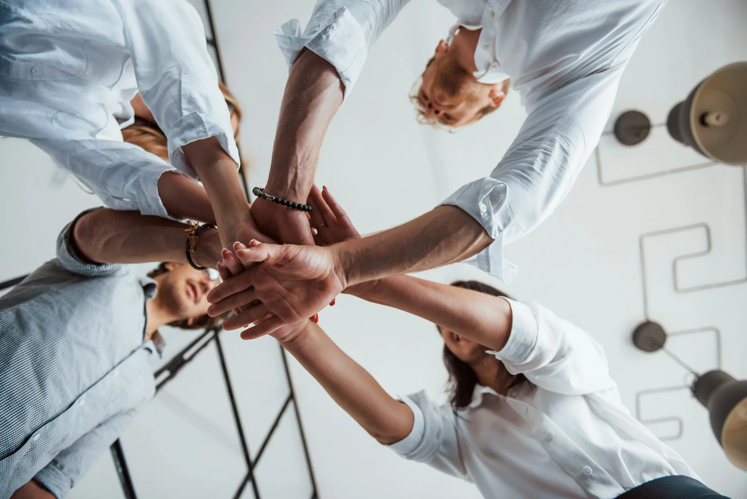 Een groep professionals die hun handen bij elkaar leggen in het midden van een cirkel